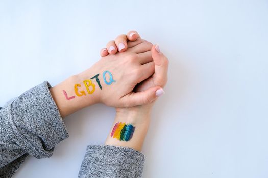 Rainbow LGBTQ flag painted on hand. Support for lgbt community. Honour of pride month. Connecting people, touching hands.