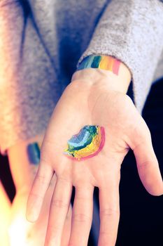 Rainbow LGBTQ flag painted on hand. Support for lgbt community. Honour of pride month. Connecting people, touching hands. Selective focus