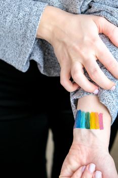 Rainbow LGBTQ flag painted on hand. Support for lgbt community. Honour of pride month. Connecting people, touching hands. Selective focus