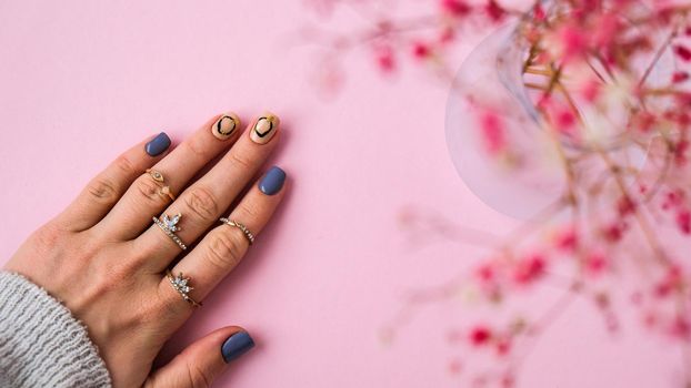 Hand in sweater and pink flowers with modern manicure nails. Female hand. Glamorous beautiful manicure. Manicure salon concept