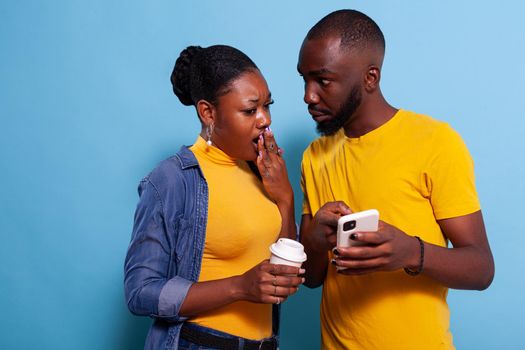 Shocked man and woman reading unexpected news on smartphone
