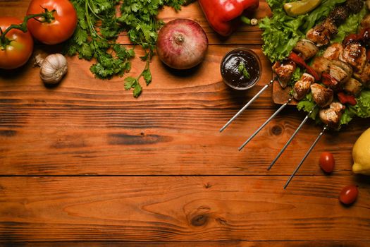 Grilled meat skewers, shish kebab with vegetables on wooden background. Top view with copy space
