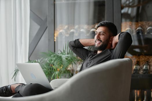 satisfied businessman with a laptop sitting in an armchair .