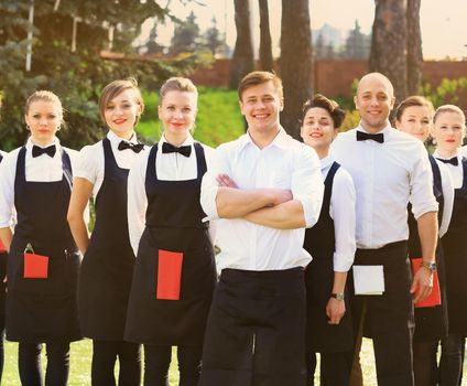 large group of cooks and waitresses stand in a row behind the chef