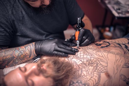 Tattooer working on professional tattoo machine device in tattoo studio