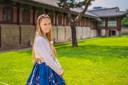 Young caucasian female tourist in hanbok national korean dress at Gyeongbokgung Palace. Travel to Korea concept. National Korean clothing. Entertainment for tourists - trying on national Korean clothing