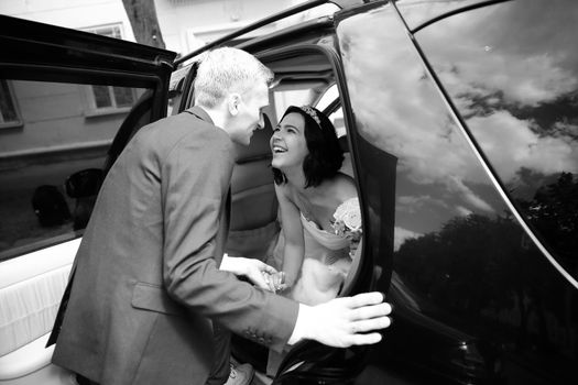 black-and-white photo .happy couple talking near wedding limo
