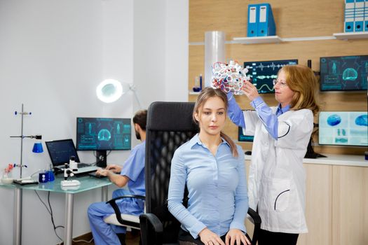 Doctor putting brainwaves scanning headset on female patient