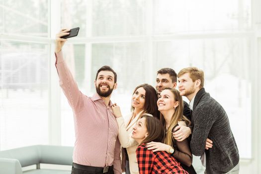 friendly business team taking a selfie while standing near window in office
