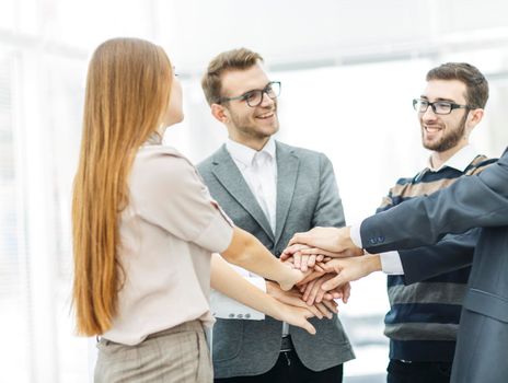 concept of success in business: friendly business team standing in a circle and joining his hands together