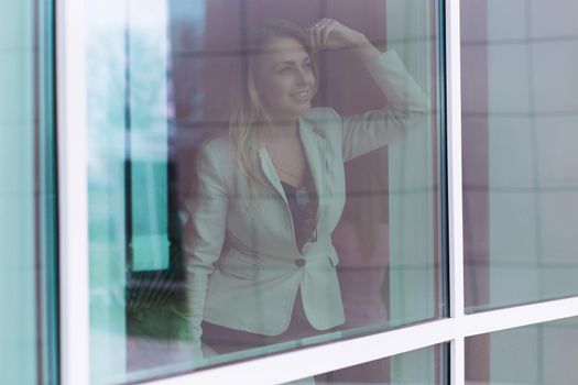 successful woman leader looks out the window of his personal office