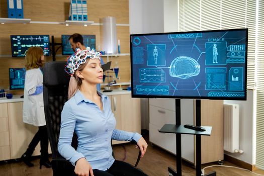 Patient woman who is brain scanned and his activity is shown on screen