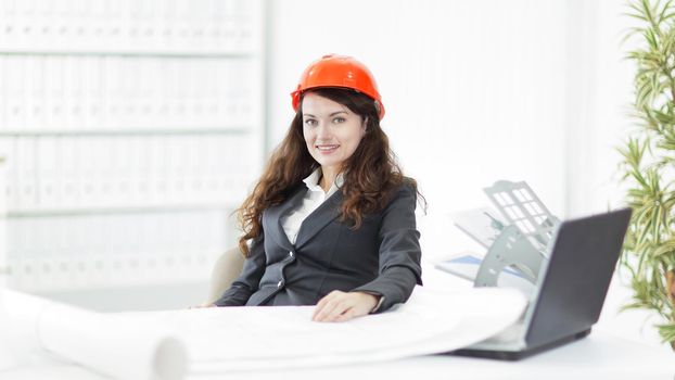 Female architect working with blueprints at office desk