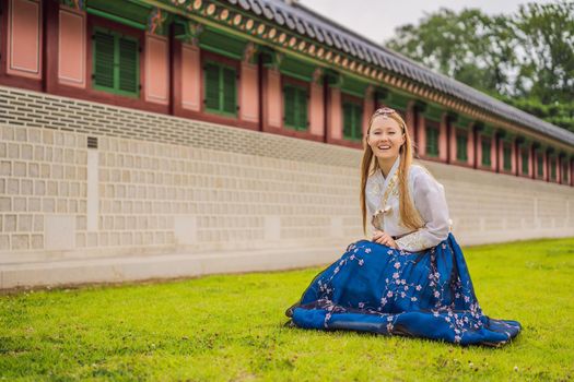 Young caucasian female tourist in hanbok national korean dress. Travel to Korea concept. National Korean clothing. Entertainment for tourists - trying on national Korean clothing