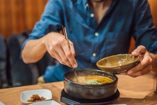 Male tourist eating Korean noodles in a Korean cafe. Travel Korea Concept