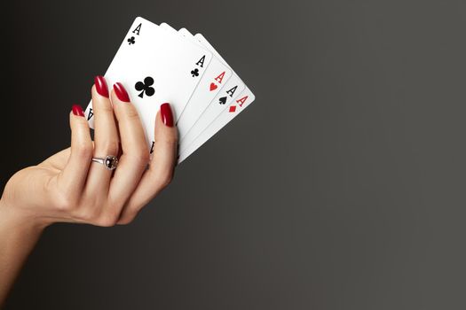 Four aces playing cards in woman's hand. Player with poker quads combination. Elegant female hands with red manicure