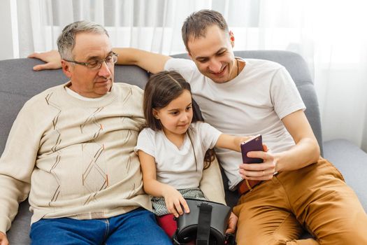 grandfather and granddaughter, father with smartphone at home
