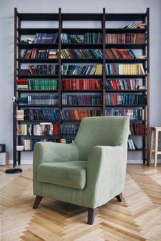 green chair in the interior. Bookcase with old books on the shelves. Books in an old wooden Cabinet
