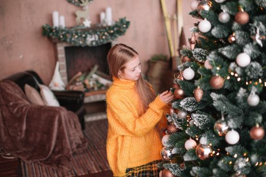 cute teen girl decorating Christmas tree in her living room