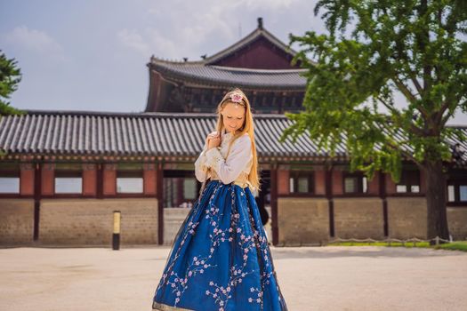 Young caucasian female tourist in hanbok national korean dress at Gyeongbokgung Palace. Travel to Korea concept. National Korean clothing. Entertainment for tourists - trying on national Korean clothing