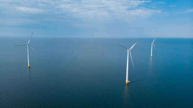 Windmill park in the ocean, drone aerial view of windmill turbines generating green energy electric, windmills isolated at sea in the Netherlands