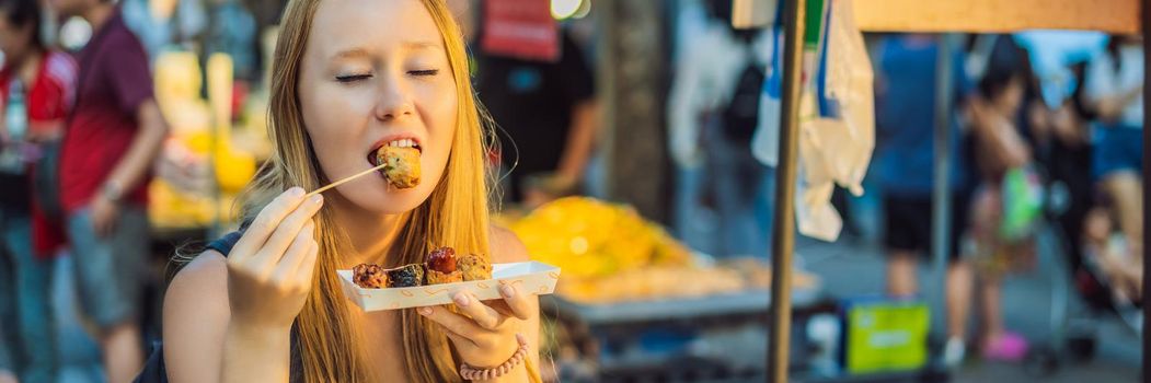 Young woman tourist eating Typical Korean street food on a walking street of Seoul. Spicy fast food simply found at local Korean martket, Soul Korea BANNER, LONG FORMAT