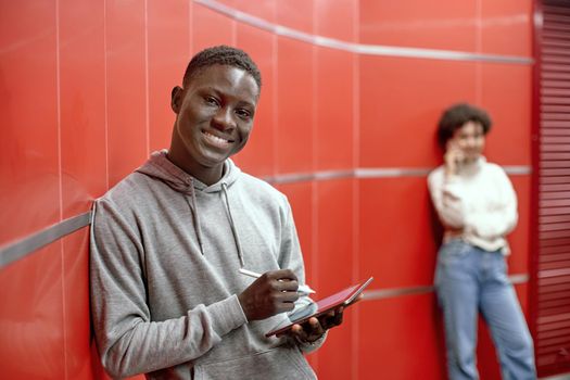 smiling guy with a digital tablet looking at the camera .