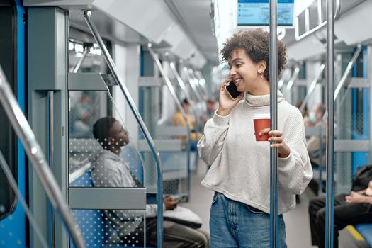 young woman with a takeaway coffee talking on a smartphone in a