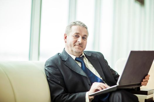 experienced businessman working on laptop sitting on sofa in a private office