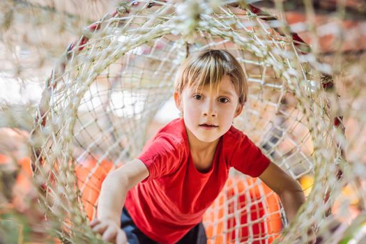 Boy crawls on a net in an obstacle course