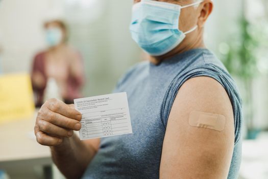 Senior Man Holding Covid-19 Vaccination Record Card