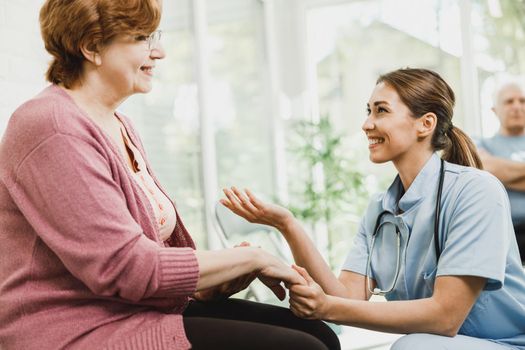 Senior Woman Talking To Caring Nurse At Waiting Room