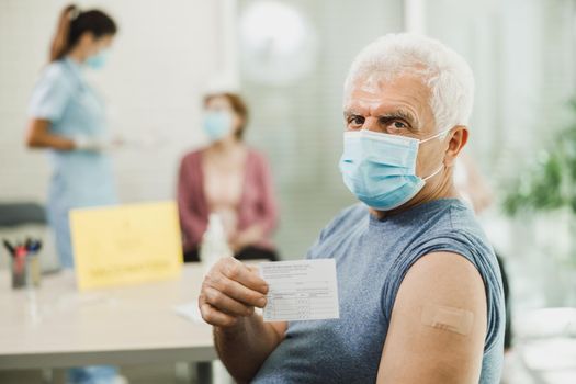 Senior Man Holding Covid-19 Vaccination Record Card