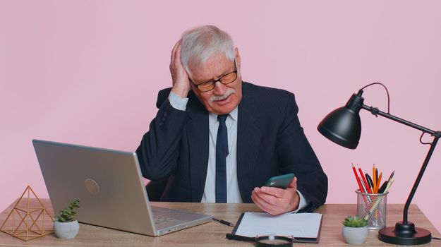 Senior businessman use smartphone typing browsing, loses surprised by lottery results, bad news