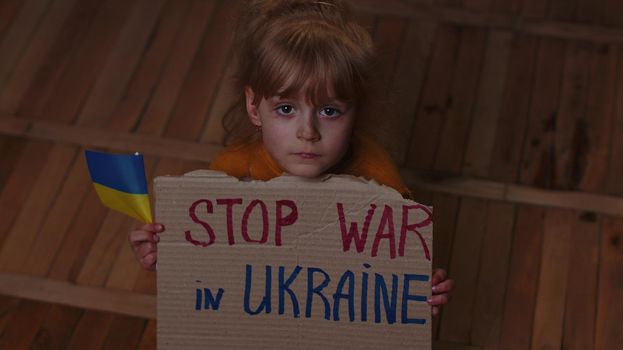 Afraid Ukrainian girl, inscription massage Stop War In Ukraine hiding from bombing attack at home