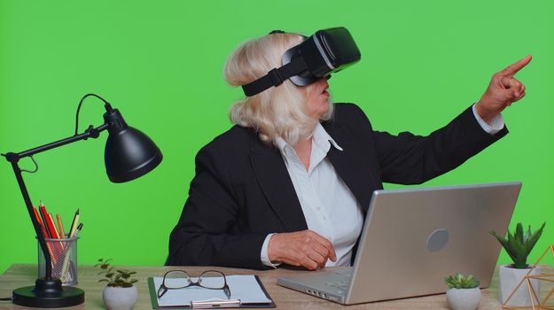 Senior businesswoman using headset helmet app to play simulation game watching virtual reality video