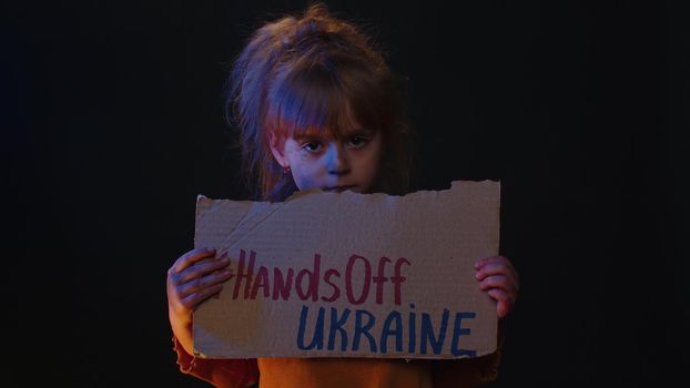 Homeless girl kid showing cardboard massage Hands Off Ukraine, crisis war, no peace, stop aggression