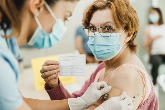 Senior Woman Holding Covid-19 Vaccination Record Card
