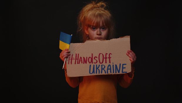 Upset poor girl homeless protesting war conflict raises banner with inscription Hands Off Ukraine