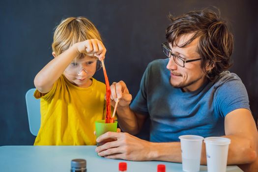 Father and son conduct chemical experiments at home. Home made slime. Family plays with a slime.