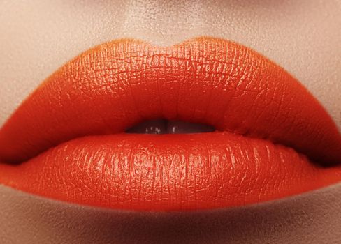 Close-up macro shot of female mouth. Sexy Glamour red lips Makeup with sensuality gesture. Orange colour