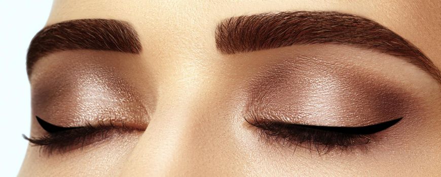 Perfect shape of eyebrows, brown eyeshadows and long eyelashes. Closeup macro shot of fashion smoky eyes visage