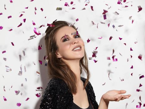 Party Time. Beautiful Happy Woman Smiling. Christmas Style in Confetti. Shiny Celebrate Look with Bright Fashion Make-up