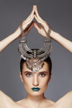 Woman with Silver Necklace in hand over head. Modern Indian Fashion Style. Jewelry Luxury Accessories. Bright Makeup