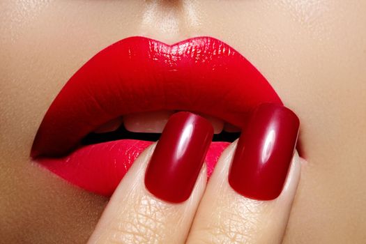 Close-up of woman's lips with fashion red make-up and manicure. Beautiful female full lips with perfect makeup