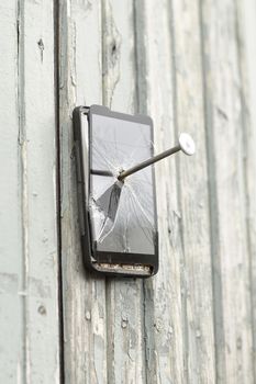 faulty mobile phone is nailed to an old fence