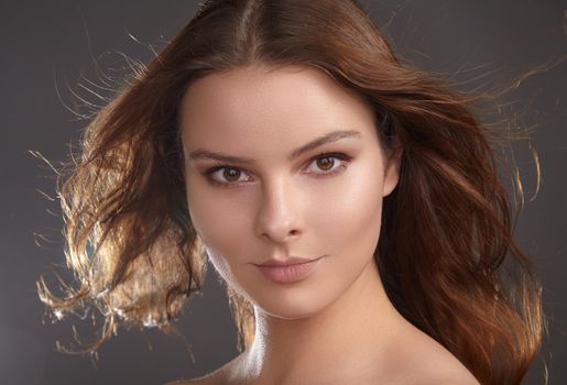 Beautiful young woman model with flying brown hair. Beauty with clean skin, fashion makeup. Make up, curly hairstyle
