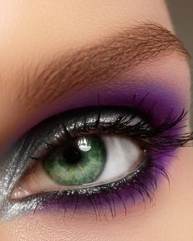 Closeup female eye with fashion bright make-up. Beautiful silver, purple eyeshadow, glitter, black eyeliner