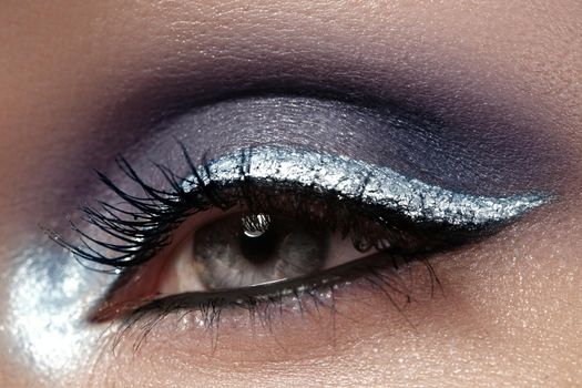 Beautiful macro shot of female eye with ceremonial makeup. Perfect shape of eyebrows, eyeliner and silver line on eyelid