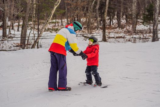 Snowboard instructor teaches a boy to snowboarding. Activities for children in winter. Children's winter sport. Lifestyle